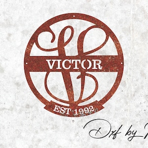 May include: A circular, rusty metal wall decoration. The name "VICTOR" is displayed prominently, with the letters "V" and "D" intertwined. The text "EST 1992" is below. The background is a textured, off-white surface.