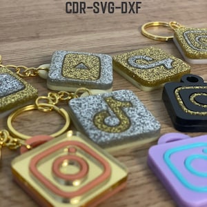 May include: NFC social media tags with various platform logos, including YouTube, Instagram, and TikTok. The tags are square-shaped with gold keychains. The text "NFC SOCIAL MEDIA TAGS CDR-SVG-DXF" is at the top.
