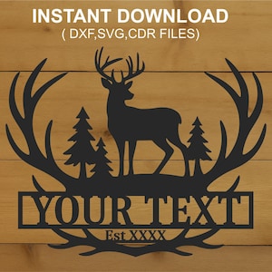 Op de afbeelding: Zwart silhouet van een hert met gewei, tussen twee dennenbomen. De tekst "YOUR TEXT" staat eronder, met "Est XXXX" eronder. Boven staat "INSTANT DOWNLOAD". Op een houten achtergrond.
