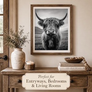 May include: Monochrome framed print featuring a Highland cow. The artwork is displayed on a wooden console table with a vase of greenery, a candle, and decorative books. The print has a rustic, farmhouse aesthetic.