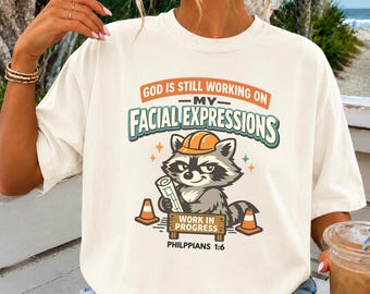 Funny Christian Shirt, God Is Still Working On My Facial Expressions Raccoon Graphic Tee