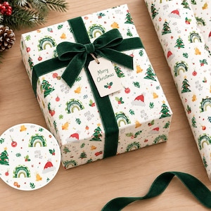 Könnte beinhalten: Ein rechteckiges Geschenkpaket in weißem Papier mit einem Muster aus grünen Weihnachtsbäumen, Regenbögen, Glocken und Weihnachtsmannmützen, gebunden mit einem dunkelgrünen Samtband und einem Anhänger mit der Aufschrift Merry Christmas.