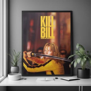 Pode incluir: Um poster de filme emoldurado para "Kill Bill" de Quentin Tarantino. O poster apresenta uma mulher em um fato de treino amarelo e preto segurando uma katana. O título "KILL BILL" está em letras amarelas grandes.