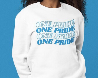 May include: White sweatshirt with the phrase "ONE PRIDE" repeated four times in a blue color, stacked on top of each other.