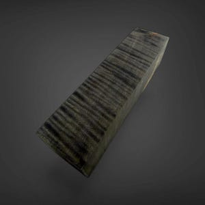 May include: A rectangular block of dark, stabilized wood featuring a prominent tiger-stripe or curly grain pattern. The surface displays deep charcoal and black tones with subtle variations in texture, showcasing the natural wood grain throughout.