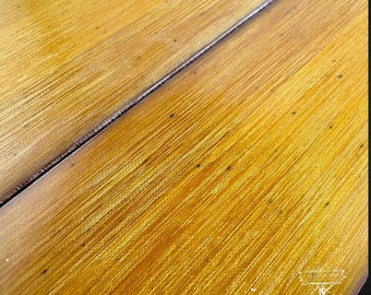 May include: Close-up of a wooden surface with a light brown colour and a fine grain pattern. The surface is divided in half by a thin, dark line. The wood has a slightly textured finish.