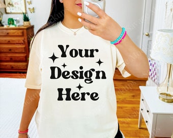 May include: A white t-shirt with the text "Your Design Here" in black with small stars on either side of the text. The model is wearing a pink baseball cap with the word "AMAM" on it.