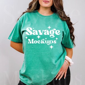 May include: A teal green t-shirt with the text "Savage Mockups" in white with a retro font and white stars.