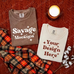 Cozy fall mockup with two folded comfort colors 1717 shirts in espresso, brown and ivory with a knitted blanket and candle in the background