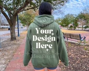Puede incluir: Una sudadera con capucha verde con el texto "Your Design Here" impreso en la espalda. La sudadera la lleva puesta una persona que camina por un camino de ladrillos.