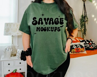 May include: A woman wearing a green t-shirt with the text "Savage Mockups" in black. She is wearing black biker shorts and has her hair pulled back in a ponytail.