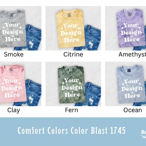May include: Six different color t-shirts with the text "Your Design Here" printed on each. The t-shirts are laid out on a white surface with a pair of blue jeans on each side.