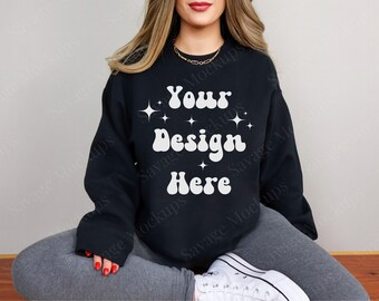 May include: A black sweatshirt with the text "Your Design Here" in white retro font with stars. The sweatshirt is being modeled by a person sitting with their legs crossed.