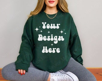May include: A dark green sweatshirt with the text "Your Design Here" in white with a retro font and white stars. The sweatshirt is being modeled by a person sitting with their legs crossed.