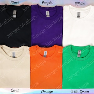 K&ouml;nnte beinhalten: Sechs gefaltete T-Shirts in verschiedenen Farben: Schwarz, Lila, Wei&szlig;, Sand, Orange und Irisch Gr&uuml;n. Jedes Shirt hat ein Etikett mit der Aufschrift "Savage Mockups".