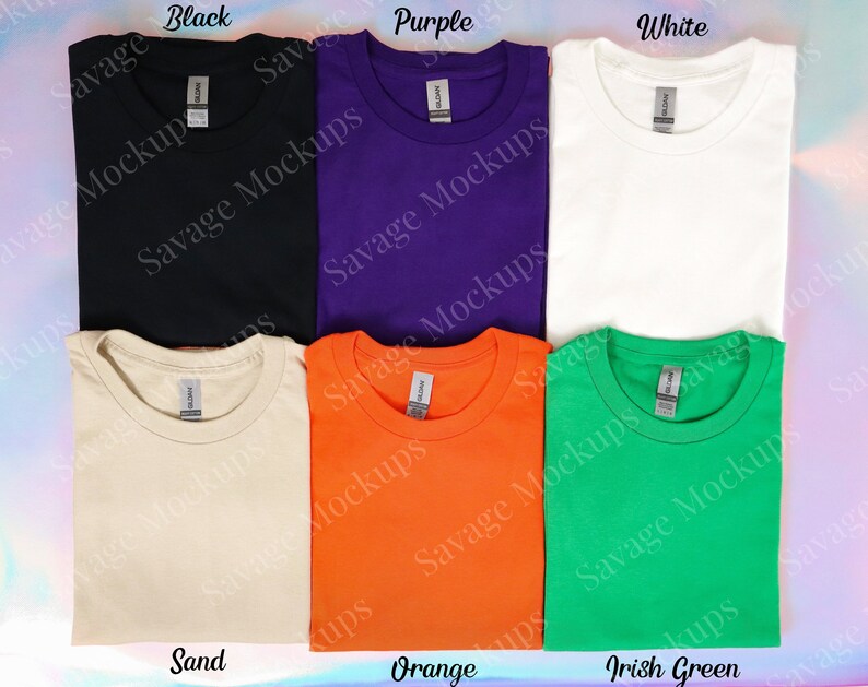 K&ouml;nnte beinhalten: Sechs gefaltete T-Shirts in verschiedenen Farben: Schwarz, Lila, Wei&szlig;, Sand, Orange und Irisch Gr&uuml;n. Jedes Shirt hat ein Etikett mit der Aufschrift "Savage Mockups".