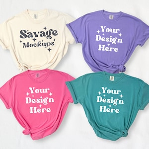 May include: Four t-shirts in different colors with the text "Your Design Here" on three of the shirts and "Savage Mockups" on the fourth shirt.