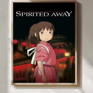 Op de afbeelding: Een ingelijste print met een personage uit de animatiefilm "Spirited Away". Het kunstwerk toont een jong meisje in een roze outfit met een witte band, tegen een achtergrond van een nachtelijk stadsbeeld met rode lantaarns. De titel "SPIRITED AWAY" staat bovenaan.
