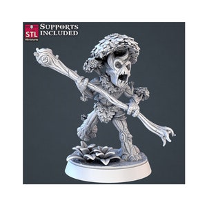 Puede incluir: Una miniatura impresa en 3D de una pequeña criatura humanoide hecha de madera y hojas. La criatura tiene un bastón en la mano y lleva una corona de hojas. La miniatura está pintada de gris claro.