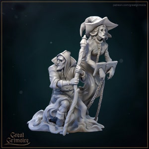 May include: A gray painted miniature figurine set depicting two figures, one a robed figure with a staff and the other a robed figure with a book and chains. The figures are posed in a dramatic scene.