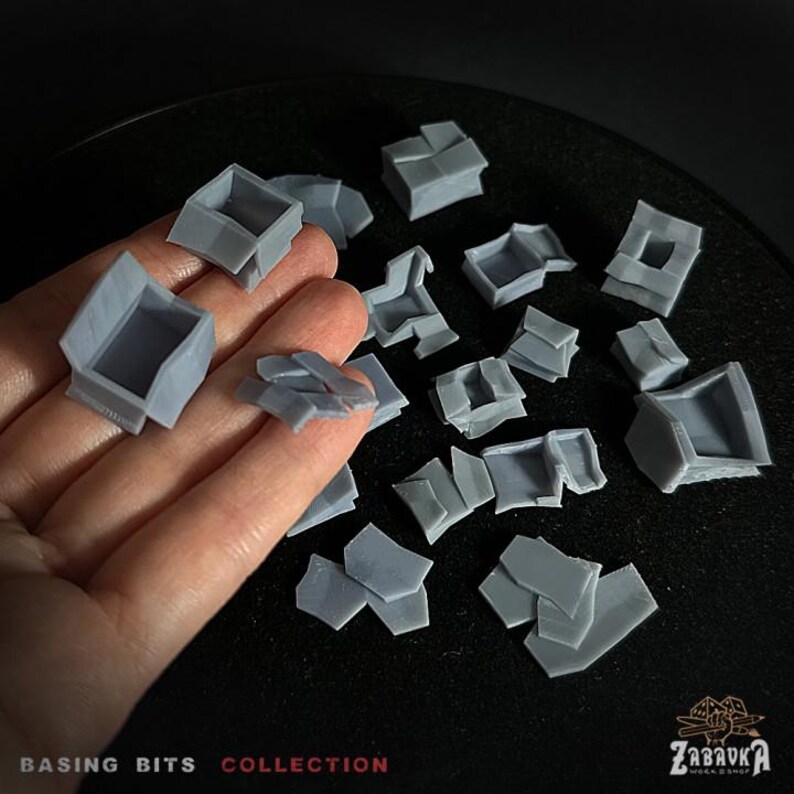 May include: A collection of gray plastic model building pieces for use in miniature wargaming or model railroading. The pieces are in various shapes and sizes, including walls, roofs, and other architectural details. The pieces are designed to be used as basing bits, which are small details that can be added to the base of a miniature to make it more visually appealing. The pieces are made of a durable plastic that can be painted and weathered to create a realistic look.