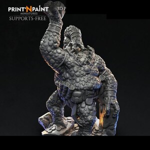 May include: A gray miniature figure of a fantasy creature, possibly a troll or ogre, with textured skin and armor. The figure is posed on a rocky base, with one arm raised. The text "PRINT 'N PAINT" and "SUPPORTS-FREE" is visible.