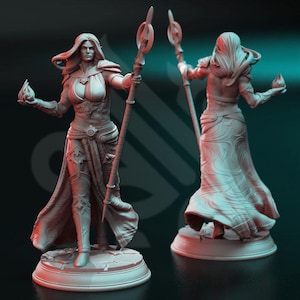 Puede incluir: Una figura en miniatura pintada de blanco de una maga sosteniendo un bastón con un orbe brillante en una mano y un orbe brillante en la otra. La figura está de pie sobre una base redonda.