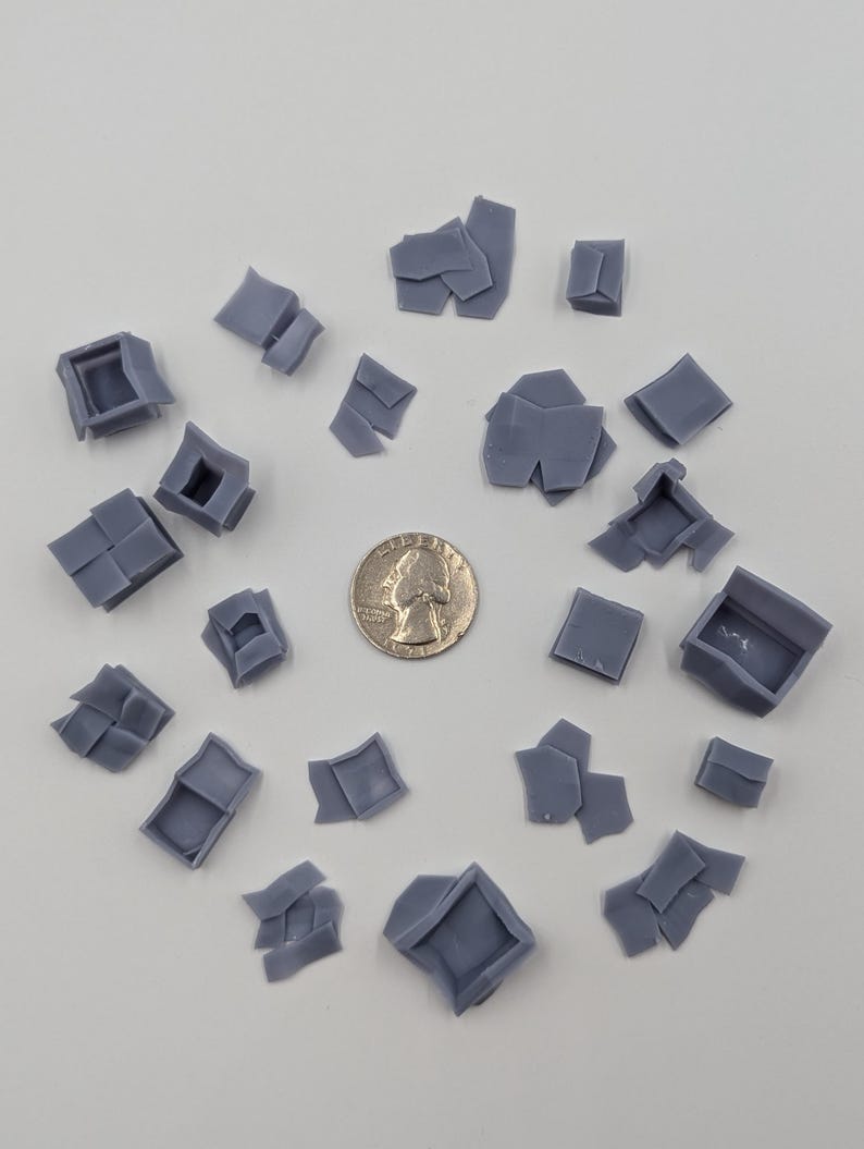 May include: A collection of 20 gray 3D printed plastic pieces, some are square, some are rectangular, and some are irregular shapes. The pieces are scattered on a white surface.