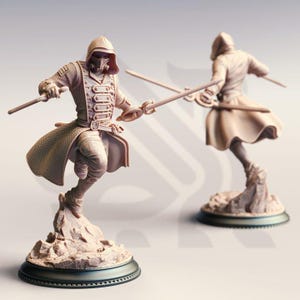 May include: Two beige figurines of a person in a hooded coat, holding swords in a dynamic pose. The figures are mounted on a rocky base with a circular, dark-colored base. One figure is in the foreground, and the other is in the background.