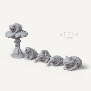 May include: Five gray toad figurines, one sitting on a mushroom, the others lined up on a white surface. The toad figurines are detailed and realistic, with textured skin and expressive faces. The mushroom is also detailed, with a textured stem and a wide, flat cap. The text "VESNA SCULPTS" is visible in the background.