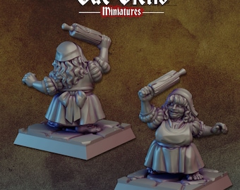 May include: Two miniature figurines of women wearing dresses and aprons, holding rolling pins. The figurines are painted in a light gray color and are standing on square bases.
