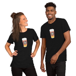 May include: Two people wearing black t-shirts. Each shirt features a graphic of a beer glass with a cartoon image inside. The beer glass has a white foamy top and a yellow and orange body. The people are smiling.