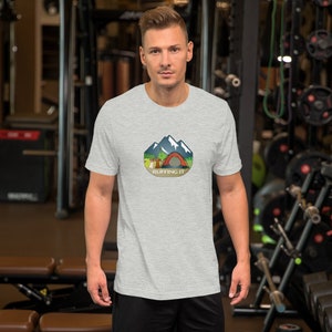 May include: A heather grey t-shirt featuring a graphic of a mountain scene with a tent and the text "Ruffing It".