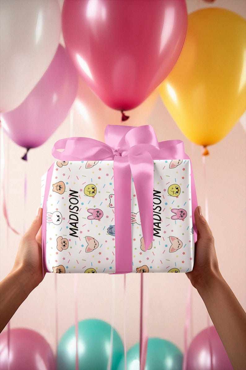 May include: A white gift box with a pink ribbon and a colorful cartoon animal print. The box is wrapped with a pink ribbon and the name "MADISON" is printed on the side.