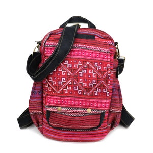 May include: Red and black patterned backpack with a black adjustable strap. The backpack has a small front pocket with two gold buttons.