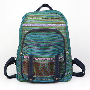 May include: A blue and green striped backpack with a woven pattern. The backpack has a large main compartment and a smaller front pocket with a flap and buckle closure.