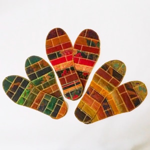 May include: Five colorful fabric shoe insoles with a patchwork design. The insoles are shaped like a foot and have a variety of colors and patterns, including red, orange, yellow, green, blue, and purple.