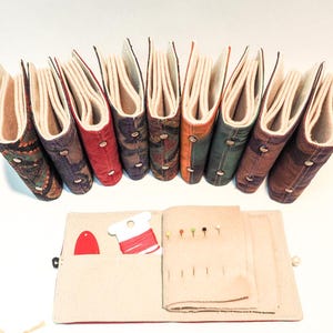 Personlig handgjord nålbok i siden med fint ullborstat flanellpapper, nålar, nålar, trädare och andra sömnadsföremål.