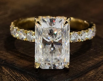 May include: A gold ring with a large, rectangular, clear diamond center stone and smaller diamonds set in the band.