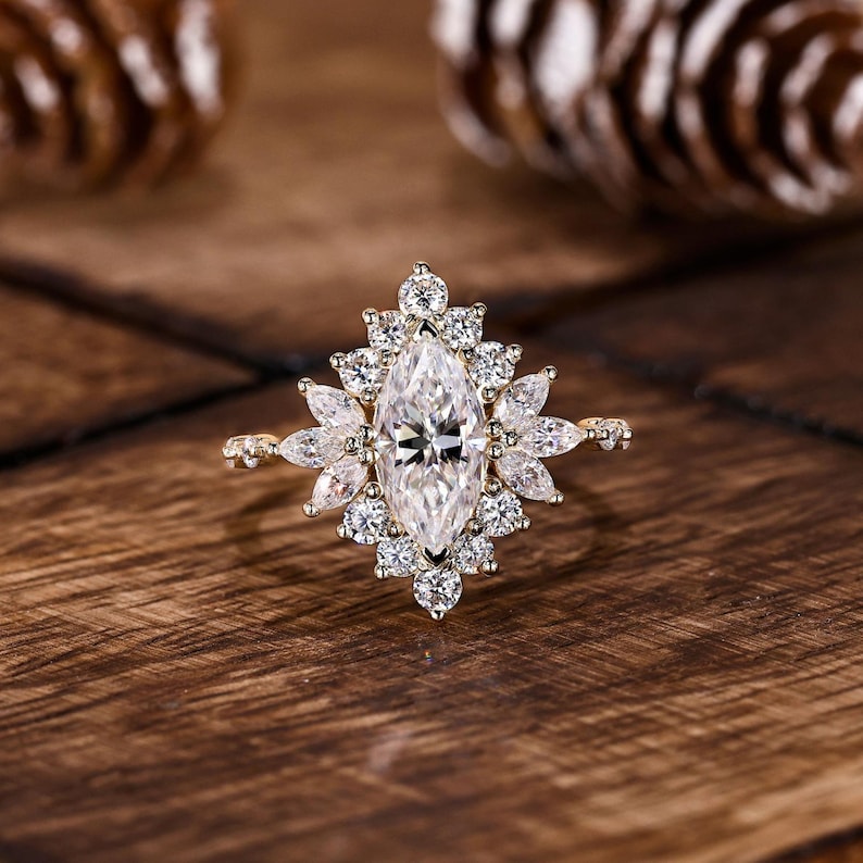 A stunning marquise-cut lab-grown diamond halo engagement ring crafted in yellow gold. The elongated 1CT marquise center diamond shines with exceptional brilliance and VVS+ clarity, surrounded by alternating round and marquise lab-grown diamonds that create a floral halo. This handcrafted design blends vintage romance with modern elegance, perfect for engagements or milestone celebrations.