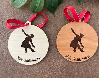 Puede incluir: Dos adornos navideños redondos de madera con cintas rojas. Cada uno presenta la silueta de un bailarín y la inscripción "Mele Kalikimaka". Uno es de madera clara, el otro más oscuro. Diámetro aproximado de 8 cm.
