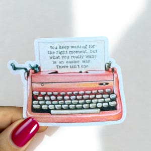 May include: A sticker featuring a vintage coral-colored typewriter with a paper insert. The paper displays the text: "You keep waiting for the right moment, but what you really want is an easier way. There isn't one."