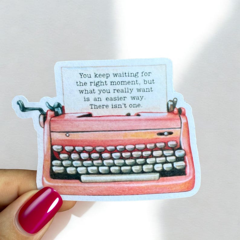 May include: A sticker featuring a vintage coral-colored typewriter with a paper insert. The paper displays the text: "You keep waiting for the right moment, but what you really want is an easier way. There isn't one."