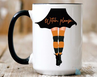 May include: White ceramic mug with a black handle. The mug features a black and orange witch's legs with a black skirt and the text "Witch, please."