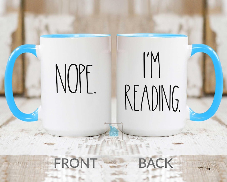 May include: White ceramic mug with a blue rim. The front of the mug says "NOPE." The back of the mug says "I'M READING."