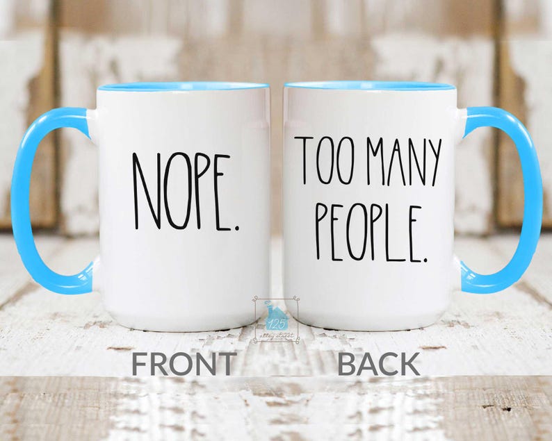 May include: Two white ceramic mugs with blue handles and interiors. One mug reads "NOPE." in black text, and the other reads "TOO MANY PEOPLE." The word "FRONT" is below the first mug, and "BACK" is below the second.