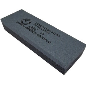May include: A grey combination sharpening stone with a black backing. The stone has the text "COMBINATION STONE 3/C FINE/COARSE NORTON 231 GRINDWELL NORTON LTD." printed on it.