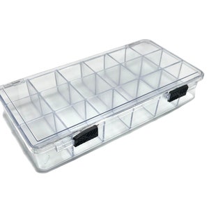 May include: A clear plastic storage box with a lid and 12 compartments. The box has black latches on the sides.