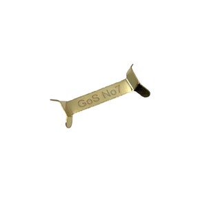 May include: A gold-coloured metal clip with the text "GoS No 7" engraved on it.