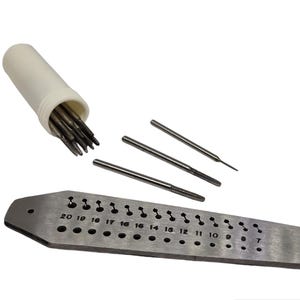 May include: A collection of metal threading tools, including taps, dies, and a metal plate with numbered holes. The tools are silver and are set against a white backdrop. A white cylindrical container holds additional tools.